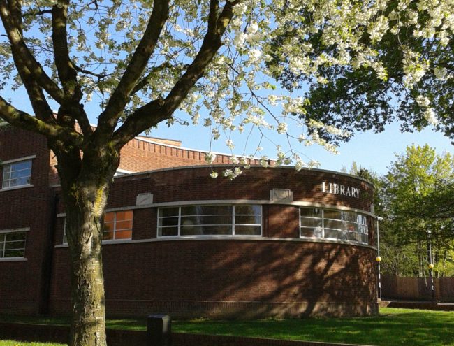Art Deco library in red brick. A large tree with white spring blossom is in the left foreground.